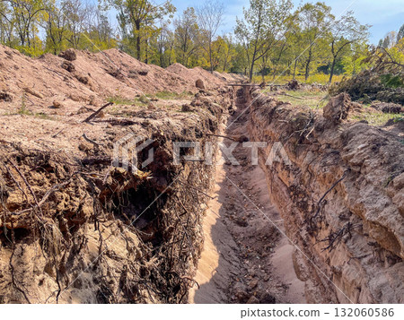 Deep Trench Dug in Sandy Soil Outdoors Deep Trench Dug in Sandy Soil Outdoors 132060586