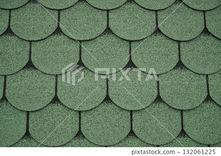 Close up of green asphalt roof shingles forming a pattern. Ideal for construction, architecture, background, or roofing design projects Close up of green asphalt roof shingles forming a pattern. Ideal for construction, architecture, background, or roofing design projects 132061225