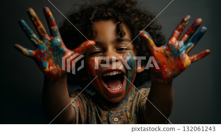 Child with Painted Hands and Face Expressing Joyful Creativity in Dark Studio Setting 132061243