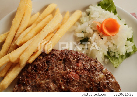 Close-up of grilled Serbian pljeskavica burger served with french fries and chopped onion on a white plate, traditional Balkan meal. Close-up of grilled Serbian pljeskavica burger served with french fries and chopped onion on a white plate, traditional Balkan meal. 132061533