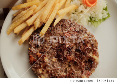 Close-up of grilled Serbian pljeskavica burger served with french fries and chopped onion on a white plate, traditional Balkan meal. Close-up of grilled Serbian pljeskavica burger served with french fries and chopped onion on a white plate, traditional Balkan meal. 132061535