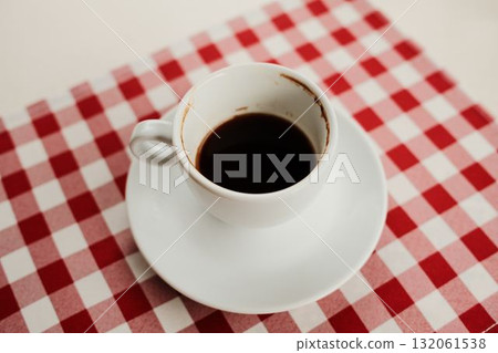 Top view of a white cup filled with black coffee placed on a red and white checkered tablecloth, minimalist breakfast concept 132061538