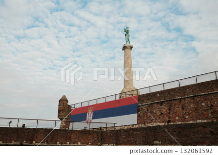Pobednik statue at Kalemegdan with Serbian flag displayed on fortress wall in Belgrade Pobednik statue at Kalemegdan with Serbian flag displayed on fortress wall in Belgrade 132061592