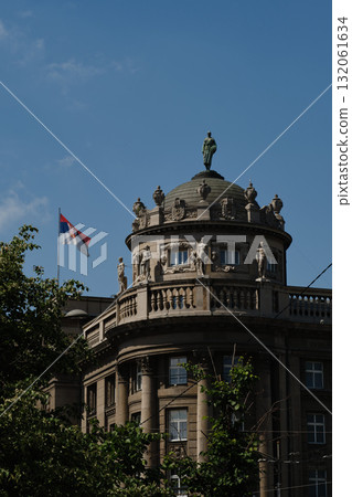 Dome of historic building in Belgrade with Serbian flag and classical statues under blue sky Dome of historic building in Belgrade with Serbian flag and classical statues under blue sky 132061634
