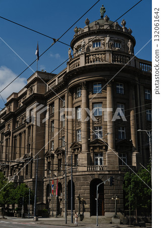 Historic government building in Belgrade with Serbian flag on facade and ornate architecture. Woman traveling with her red merle Border Collie puppy, posing on city street 132061642