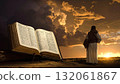 Biblical scene depicting a figure in robes gazing at a sunset with an open Bible in the foreground showing ancient text 132061867