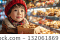 Little boy with Christmas cookies shopping for gifts in festive market filled with lights and decorations 132061869