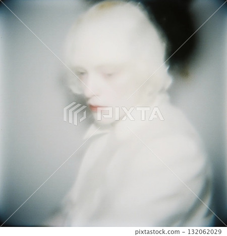 A sad pale harlequin clown sits quietly in a dimly lit space. The expression on the clown's face reflects deep emotions. Soft lighting enhances a somber mood Generative AI 132062029