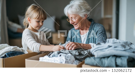 Grandmother and child joyfully organizing donated clothes together, showcasing multigenerational family life and emotional connection in a cozy setting Grandmother and child joyfully organizing donated clothes together, showcasing multigenerational family life and emotional connection in a cozy setting 132062172