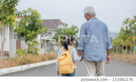 Black grandfather holding hands with his Asian granddaughter, walking together down a quiet street, showcasing multigenerational family connection Black grandfather holding hands with his Asian granddaughter, walking together down a quiet street, showcasing multigenerational family connection 132062176