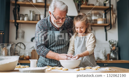 Grandpa and granddaughter joyfully baking cookies together in a cozy kitchen, showcasing multigenerational family life and emotional connection 132062190