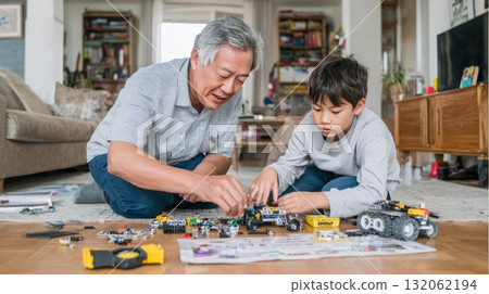 Latino grandpa and his Asian grandson are building toy vehicles together on the floor, showcasing a multigenerational family bonding moment Latino grandpa and his Asian grandson are building toy vehicles together on the floor, showcasing a multigenerational family bonding moment 132062194