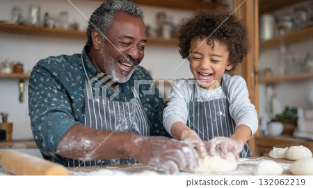 Black grandfather joyfully baking with his biracial grandson in a cozy kitchen, showcasing multigenerational family bonding and emotional connection 132062219