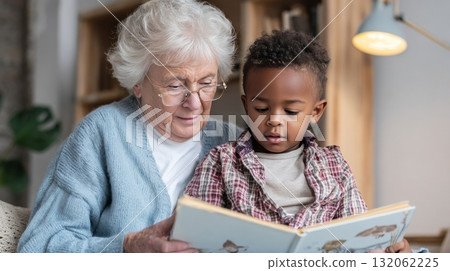 Grandmother reading a book to young black boy in cozy living room, showcasing multigenerational family life and emotional connection Grandmother reading a book to young black boy in cozy living room, showcasing multigenerational family life and emotional connection 132062225