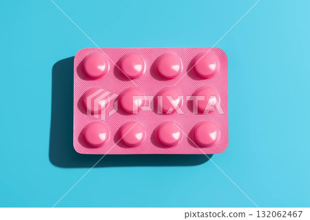 Pink blister pack of round tablets on a vibrant blue background for health and wellness concepts 132062467