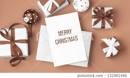 Merry christmas background, paper holiday greeting card with gift boxes and xmas ball on mocha mousse color background Merry christmas background, paper holiday greeting card with gift boxes and xmas ball on mocha mousse color background 132062480
