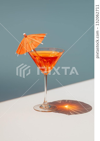 Vibrant cocktail with orange umbrella garnished in elegant glass on minimalistic background 132062711