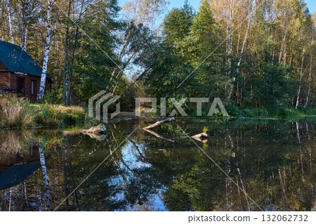 Tranquil Reflections: House and Trees Mirrored in River Tranquil Reflections: House and Trees Mirrored in River 132062732