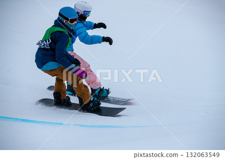 Male and female snowboarders in competition race snowboard cross Male and female snowboarders in competition race snowboard cross 132063549