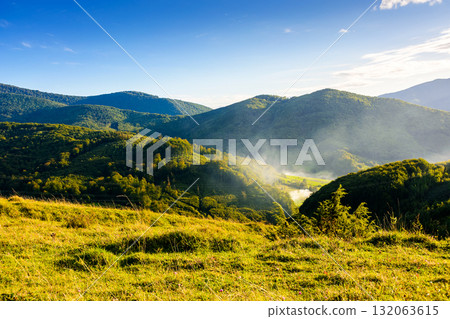 countryside mountain landscape in autumn. rural field on green hill. beautiful scenery with grassy meadow and forested slope in highland of ukraine under blue sky. scenic carpathian view in afternoon 132063615