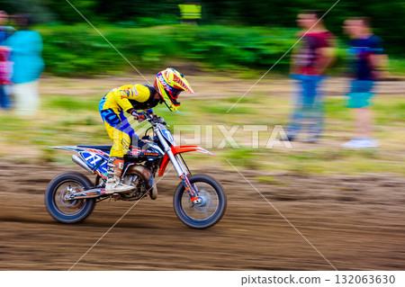 uzhhorod, ukraine - may 21, 2017: junior mx rider turns on a corner. motocross track through forest. extreme sport with flying dirt during accelerating uzhhorod, ukraine - may 21, 2017: junior mx rider turns on a corner. motocross track through forest. extreme sport with flying dirt during accelerating 132063630