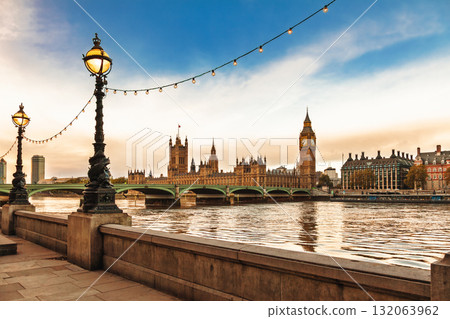 Palace of Westminster and Big Ben viewed from the South Bank with historic lamps and string lights over River Thames 132063962