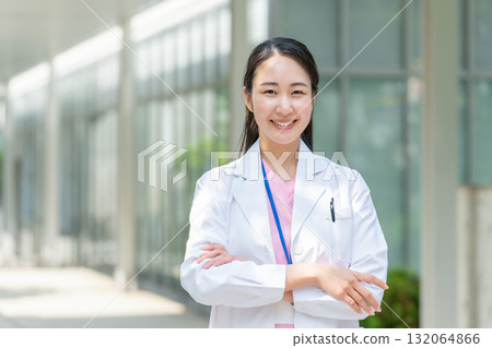 Woman in white coat outdoors arms crossed Woman in white coat outdoors arms crossed 132064866