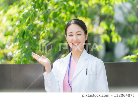 戶外穿白大褂的女人,新鮮的綠色植物,揮手 戶外穿白大褂的女人,新鮮的綠色植物,揮手 132064875