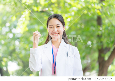 戶外穿白大褂的女人,新鮮的綠色植物,拳頭泵 戶外穿白大褂的女人,新鮮的綠色植物,拳頭泵 132064896