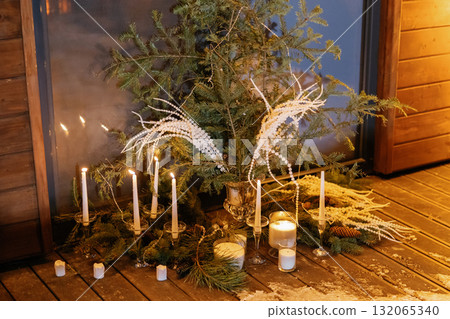 Christmas candles illuminating fir branches and woven baskets on a wooden surface 132065340