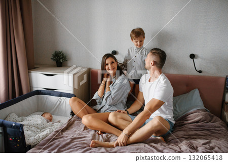 Young Family Sitting Together In Bedroom With Newborn 132065418