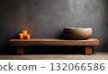 Serene spa setting with stone bowl and lit candles on wooden bench against textured wall 132066586