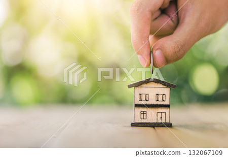 House is placed on the table. hands putting coins into the house. planning savings money of coins to buy a home concept for property, mortgage and real estate investment. 132067109