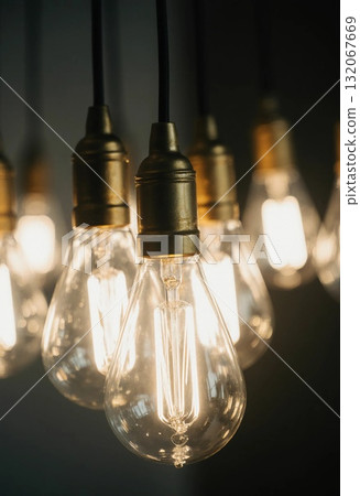 Bright garland light bulbs hang gracefully from the ceiling, casting a warm glow in a cozy indoor setting during the evening, creating a welcoming atmosphere Generative AI 132067669