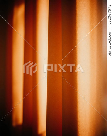 Soft light illuminates the red curtains hanging in a tranquil room. The warm glow creates a peaceful atmosphere, inviting relaxation during the evening Generative AI 132067672