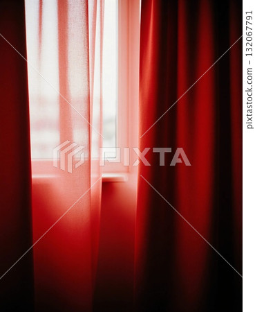 Sunlight gently passes through red curtains in a cozy room, creating a warm, inviting atmosphere. The vibrant color adds energy to the space, enhancing the peaceful vibe Generative AI 132067791