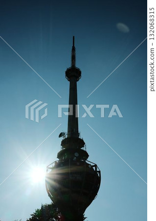 Silhouette of TV tower Iriki Venac at Fruska Gora with bright sun rays shining behind the structure. Destroyed by NATO missile during the Yugoslav war, standing above forest trees Silhouette of TV tower Iriki Venac at Fruska Gora with bright sun rays shining behind the structure. Destroyed by NATO missile during the Yugoslav war, standing above forest trees 132068315