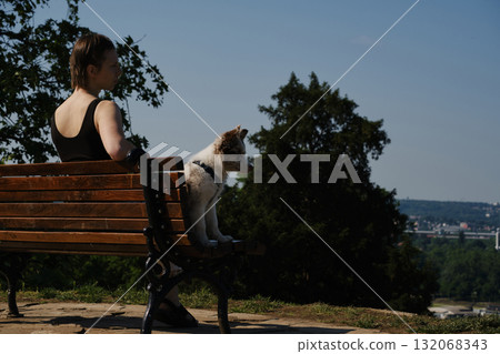 Smiling young woman with her red merle border collie puppy sitting on a bench in Kalemegdan Fortress, Belgrade, with city view in background Smiling young woman with her red merle border collie puppy sitting on a bench in Kalemegdan Fortress, Belgrade, with city view in background 132068343