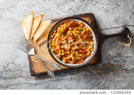 Spanish vegetable stew with cabbage, chickpeas, chorizo and paprika close-up in a plate. Horizontal top view 132068348