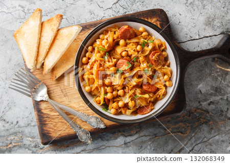 Delicious winter food: cabbage stewed with chickpeas, chorizo and paprika close-up in a plate. Horizontal top view 132068349