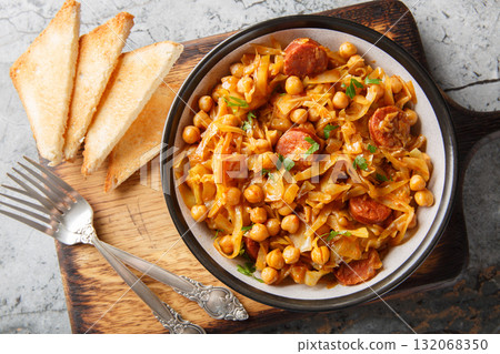 Spanish Cabbage and Chickpeas known as col con garbanzos with the addition of paprika and chorizo sausages on a plate. Horizontal top view 132068350