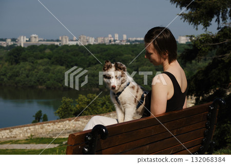 Woman with border collie puppy sitting on wooden bench in Kalemegdan Fortress, Belgrade, overlooking the Sava River Woman with border collie puppy sitting on wooden bench in Kalemegdan Fortress, Belgrade, overlooking the Sava River 132068384