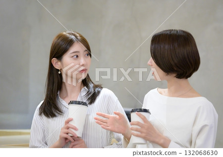 Women having a conversation while drinking coffee in a cafe 132068630