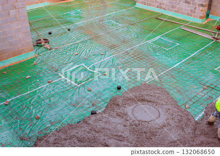 Workers pouring fresh concrete mix for foundation with rebar grid in construction area 132068650