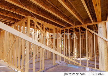 Workers are framing new home, showcasing wooden structures beams open spaces in construction area. 132068666