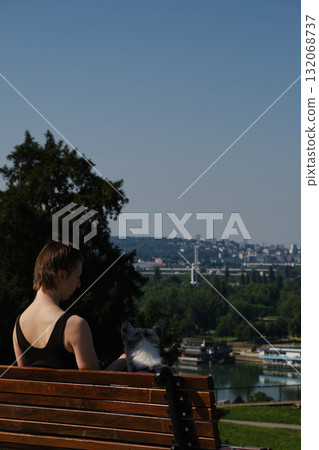 Woman with border collie puppy sitting on wooden bench in Kalemegdan Fortress, Belgrade, overlooking the Sava River 132068737