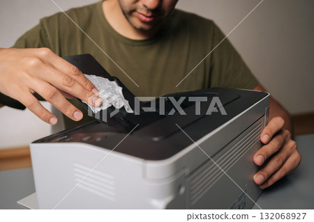 Cropped shot of technician cleaning printer with cloth, performing routine maintenance on essential office equipment, ensuring smooth operation and preventing malfunctions on isolated background 132068927