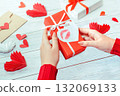 a girl holds a Valentine's Day gift with a message and paper hearts around 132069133