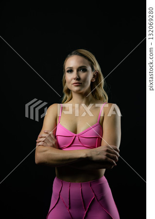 Confident fitness model posing in pink sportswear on black background 132069280