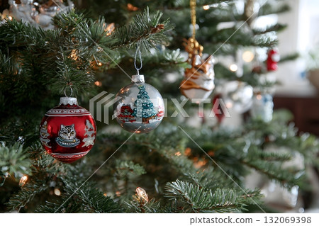 Christmas ornaments hang on a green pine tree branch. Christmas ornaments hang on a green pine tree branch. 132069398